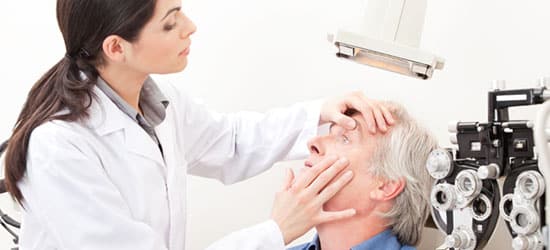 ophthalmologist performing eye exam, checking eye of elderly male patient