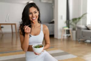 Young woman eating a healthy salad after workout.