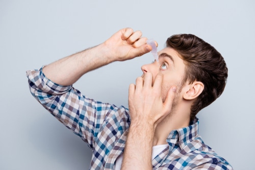 side view of a man in checkered shirt applying eye drop