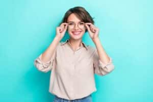 woman with bob hairdo dressed beige blouse hands hold glasses